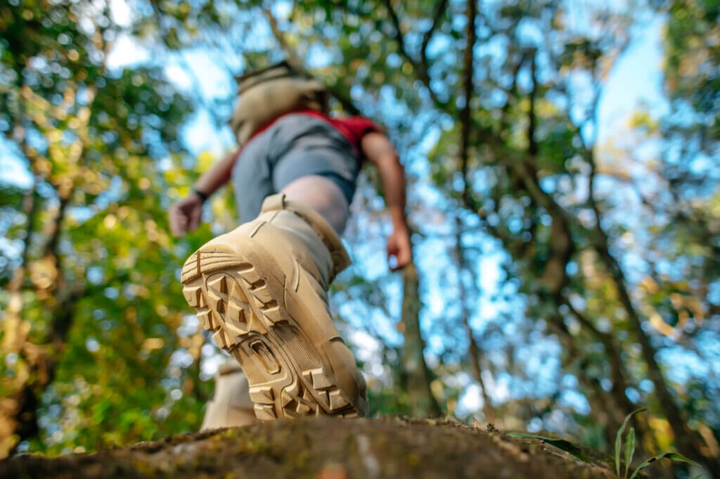 close up rear view trekking shoes hiker walking rock forest trail with sunlight copy space